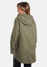 Olivegrüne Kapuzenjacke mit lockerer Passform, tailliertem Schnitt, langen Ärmeln und abgerundetem Saum. Hergestellt aus Baumwollstoff.