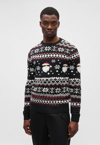 Sweater de Natal preto com rostos de Pai Natal, flocos de neve e padrões geométricos em branco e vermelho. Punhos e bainha canelados. Tecido em mistura de algodão.