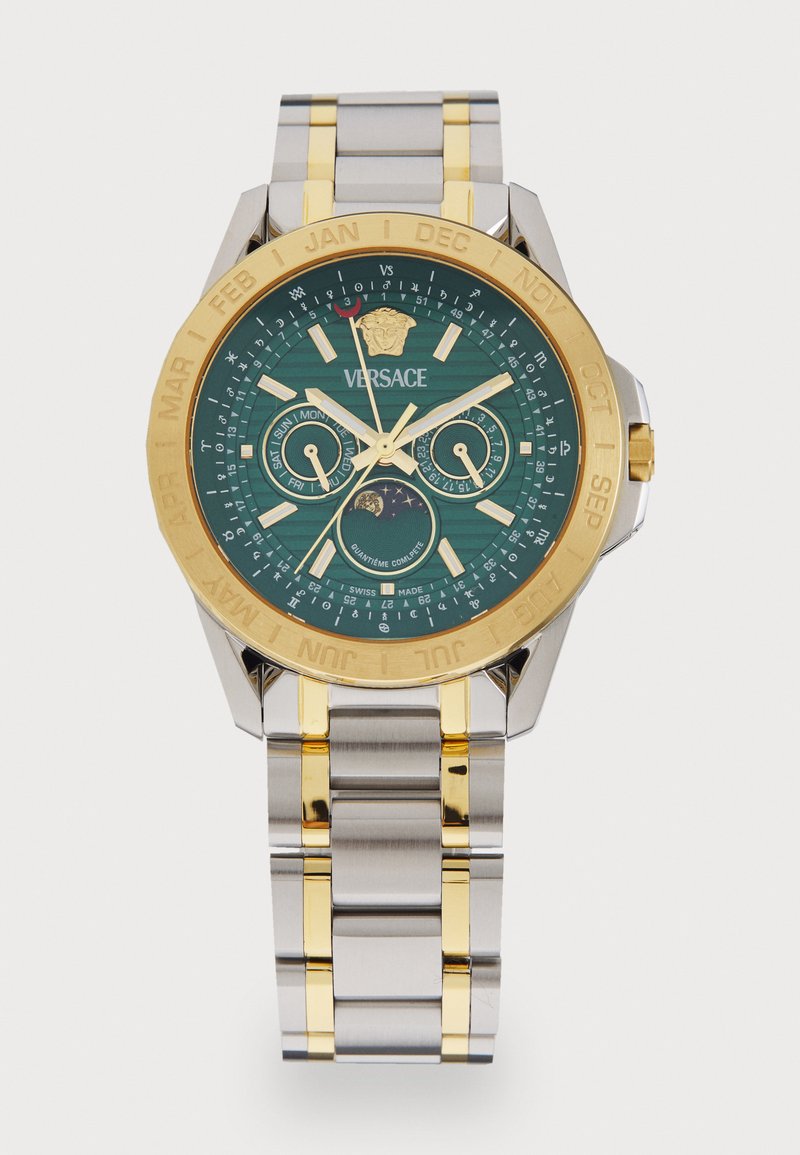 Ρολόι Versace με πράσινο καντράν, χρυσές λεπτομέρειες και ατσάλινη αλυσίδα σε ασημί απόχρωση. Περιλαμβάνει υποκαντράν και λογότυπο λιονταριού στη θέση 12.