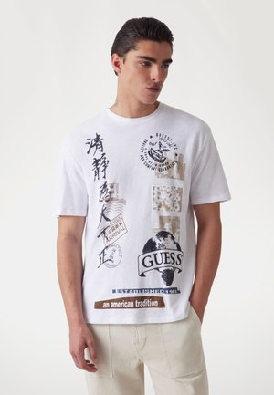 Hvid bomulds t-shirt med forskellige grafiske tryk, herunder en globe og tekst i sort og brunt, med korte ærmer og et klassisk fit.