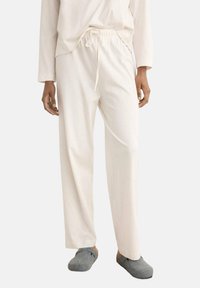Pantalons beige clair, à coupe ample, avec une taille élastique et un cordon de serrage. Fabriqués en tissu doux avec une texture lisse.