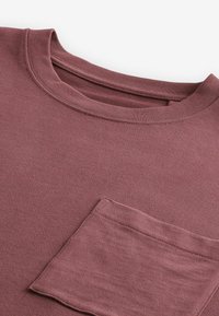 Mörkerød langærmet t-shirt med rund halsudskæring og en brystlomme, lavet af letvægtsstof med en glat tekstur.
