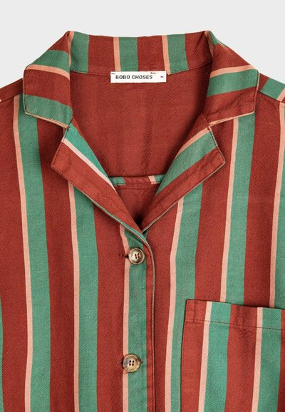 Košeľa s pruhovaným vzorom a golierom, v zelených, hrdzavých a béžových farbách. Dva gombíky a náprsné vrecko na ľavej strane.