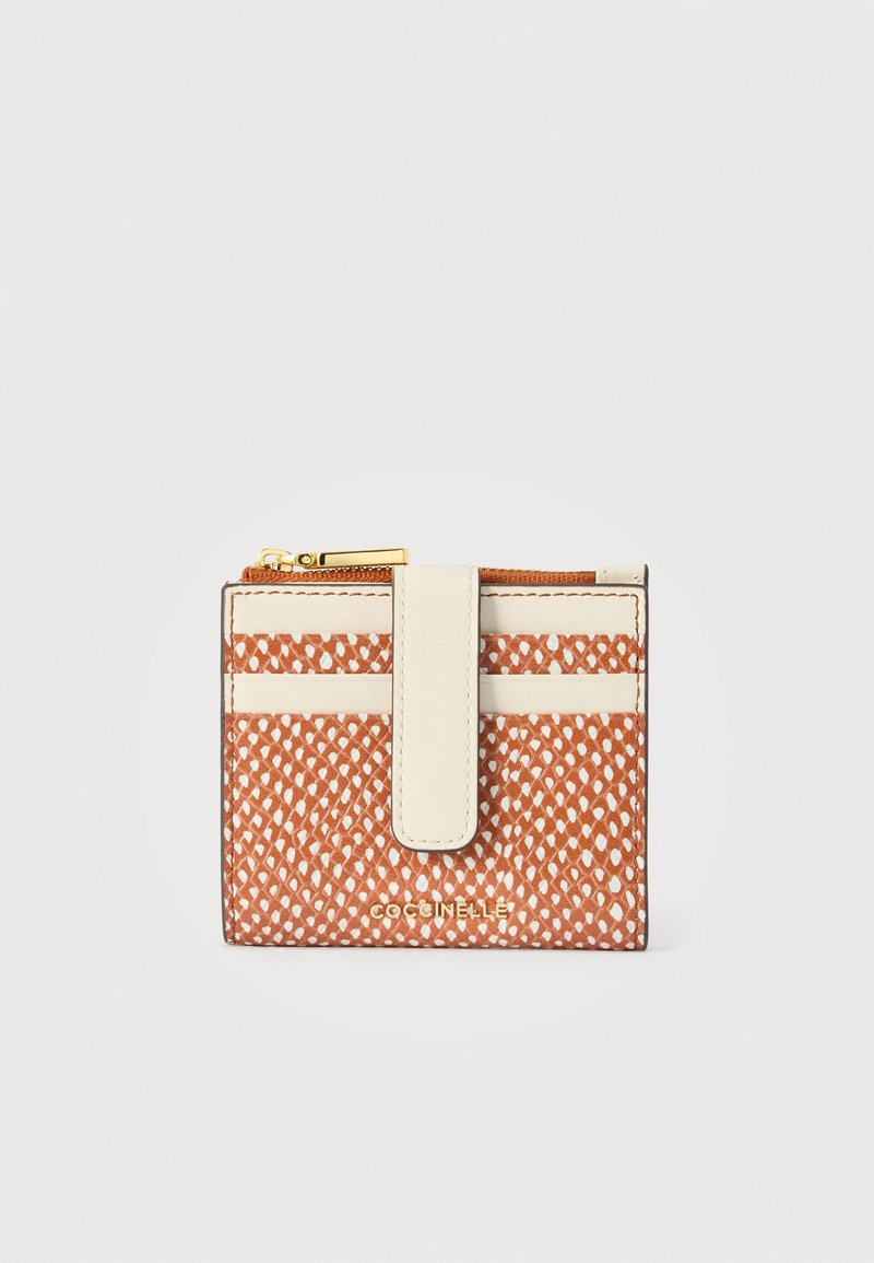 Συμπαγές πορτοφόλι με καφέ και λευκό μοτίβο, με κρεμί λουράκι και χρυσό φερμουάρ, με το όνομα της μάρκας "Coccinelle" στο μπροστινό μέρος.