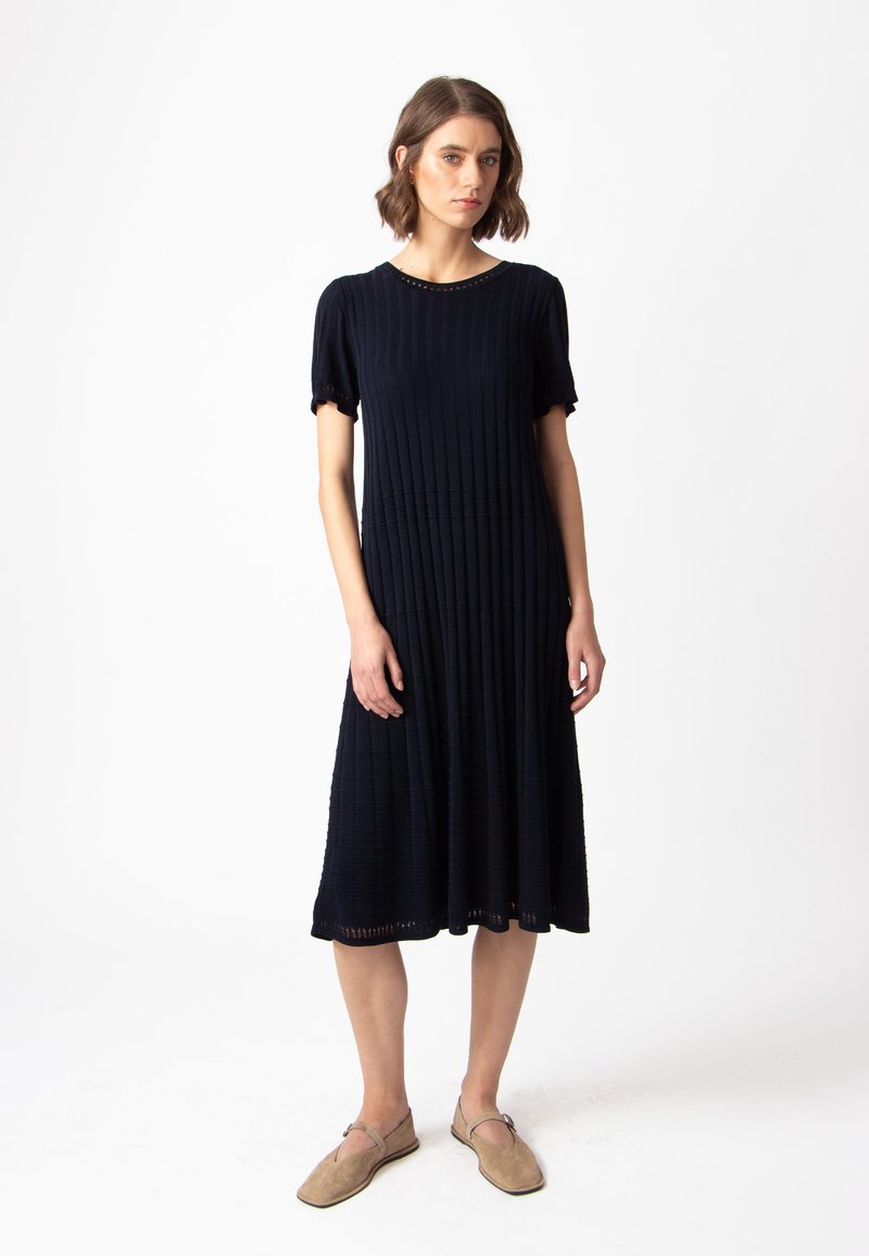 Mornarska rebrasta midi haljina s kratkim rukavima, okruglim izrezom, teksturiranim uzorkom i detaljima na rubu, u kombinaciji s bež ravnim cipelama.