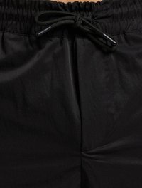 Shorts légers noirs avec une taille élastique, détail de cordon de serrage et texture lisse, affichant un éclat subtil et sans poches visibles.
