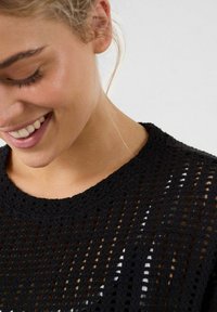 Zwarte gebreide top met een ronde halslijn, met een opengeweven patroon. De structuur is lichtgewicht, perfect voor het laagjes dragen.