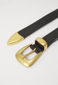 Ceinture en cuir noir avec une boucle en métal doré et une pointe. Présente une boucle rectangulaire et une pointe effilée avec une texture lisse et sans motifs.
