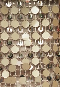 Des paillettes dorées de formes variées, incluant des gouttes et des cercles, sont finement cousues sur une base de tissu doux, créant une surface texturée et scintillante.