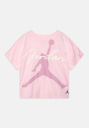 Różowa bawełniana koszulka z okrągłym dekoltem. Ma dużą czerwoną sylwetkę Jumpman i tekst "Jordan" w białym kolorze. Krótkie rękawy, luźny krój.