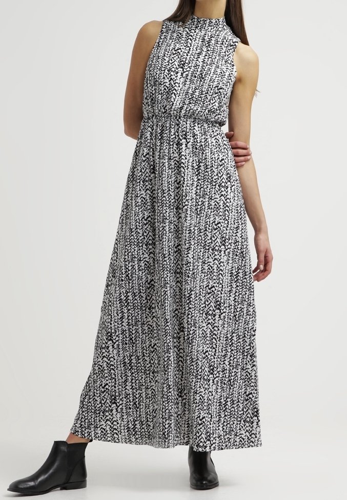 Maxi dress in black and white abstract pattern, sleeveless with high neckline, fitted waist, flowing skirt, paired with black ankle boots.