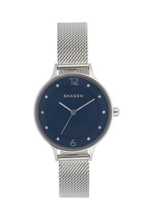 Srebrny zegarek na siateczkowym pasku z niebieską tarczą, minimalistycznymi znacznikami i srebrnymi wskazówkami wskazującymi 10:10:35, marki Skagen.