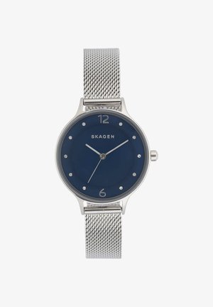 Montre bracelet en maille argentée avec cadran bleu, index minimalistes et aiguilles argentées indiquant 10:10:35, marque Skagen.