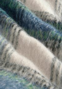 Tessuto in misto lana caratterizzato da morbide trame, blu e verdi prominenti con strisce bianche e grigie, creando un aspetto stratificato e accogliente.