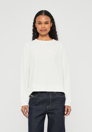 Lichtbeige sweatshirt met een ronde halslijn, een drop shoulder ontwerp en een zachte textuur. Voorzien van een reliëflogo in een subtiele roze tint.