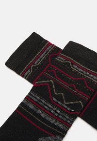 Los calcetines de lana negros presentan un diseño estampado con líneas y formas en rojo, gris y verde oliva. Tejido texturizado con un puño acanalado.
