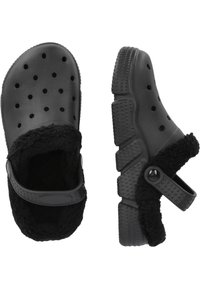 Sabots noirs avec un extérieur en caoutchouc texturé, dotés de trous de ventilation et d'une doublure douce et pelucheuse. Comprend une sangle ajustable pour plus de sécurité.