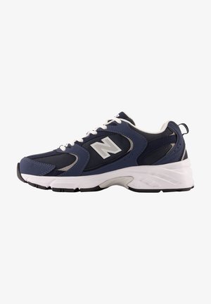 Zapatilla deportiva azul marino y negra con suela y cordones blancos, paneles de malla y un gran logo "N" en el lateral.