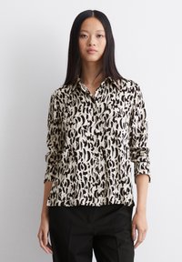 Langärmliges Hemd in Beige und Schwarz mit einem abstrakten Tiermuster, das einen Kragen und einen lockeren Schnitt aufweist.