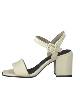 Beige sandal med åben tå, blokhæl og ankelrem med en firkantet spænde, med sort indersål.