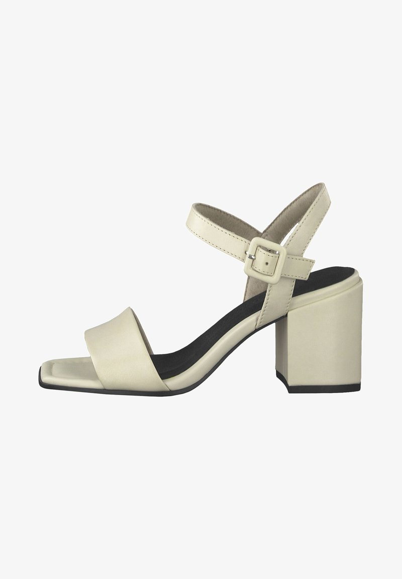 Sandale beige à bout ouvert avec un talon bloc et une bride à la cheville sécurisée par une boucle carrée, avec une semelle intérieure noire.