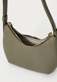 Borsa a tracolla verde oliva realizzata in materiale testurizzato con una forma curva. Presenta una cerniera dorata e un compartimento interno grigio.