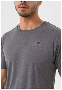 Grå kortærmet T-shirt lavet af blødt stof. Har rund hals og et lille sort logo på brystet, glat tekstur.