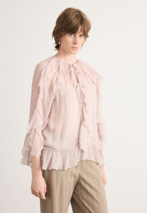 Lichtroze blouse van doorschijnende stof, met rucheslangs de mouwen en halslijn en een licht uitlopende zoom.