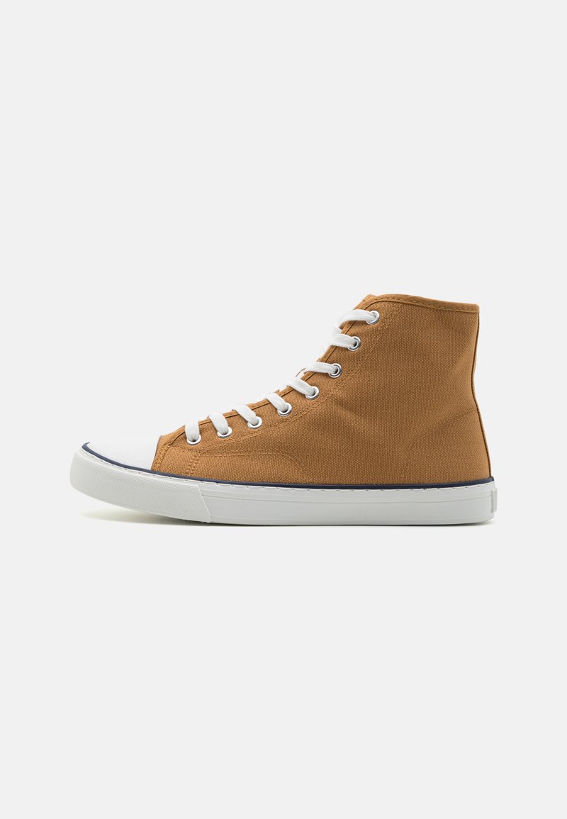 Høye sneakers i brunt lerret med hvit gummikappe og såle, med hvite lisser og kontrasterende blå sømmer langs sålen.