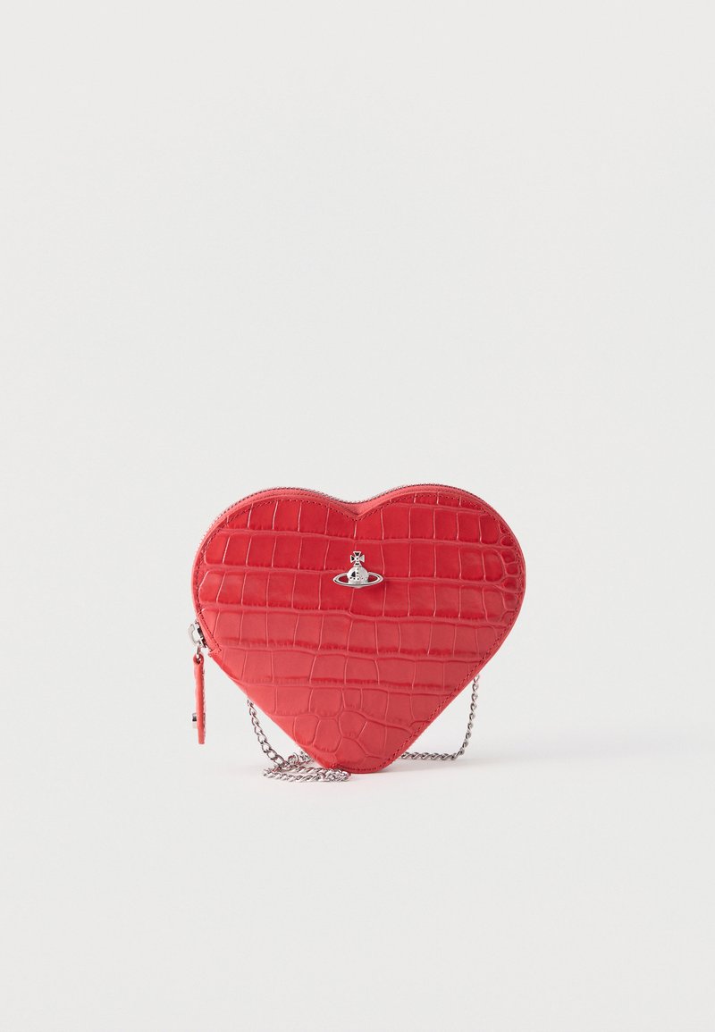 Sac à main rouge en forme de cœur avec texture crocodile, logo sphère argentée, fermeture éclair et bandoulière chaîne argentée sur fond blanc.