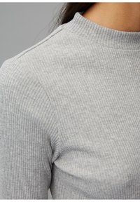 Grau gerippter Rollkragenpullover mit passgenauer Silhouette, der einen hohen Kragen und strukturierten Stoff aufweist und Wärme sowie Komfort betont.