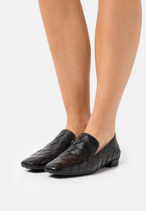 Scarpe slip-on in pelle intrecciata nera con tacco basso e punta affusolata, caratterizzate da una superficie testurizzata e dettagli lisci.