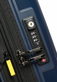 Maleta azul con una superficie texturizada, que cuenta con un candado aprobado por la TSA, un disco numérico y cremalleras negras con una pestaña amarilla de Delsey.