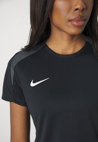 Mustast sportlike s�ärgist, millel on tekstuuriga materjal, hallid aktsendid õlgadel ja valge Nike swoosh logo rindel.