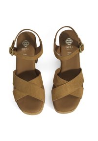 Bruine suede sandalen met kruislings banden, open teen en enkelgesp. Korken middenzoolaccenten. Merklogo op de binnenzool. Plat hielontwerp.