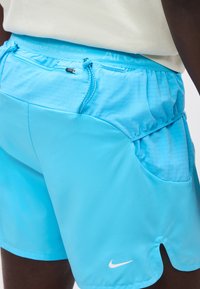 Μπλε αθλητικό σορτς με τσέπη με φερμουάρ στο πίσω μέρος, ρυθμιζόμενα κορδόνια και λευκό λογότυπο Nike στο μπροστινό δεξί πόδι.