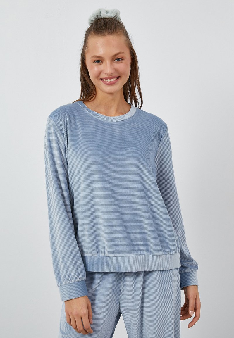 Jasnoniebieska bluza crew-neck z ribbowymi mankietami i dołem, wykonana z miękkiej, teksturowanej tkaniny, o luźnym kroju i długich rękawach.