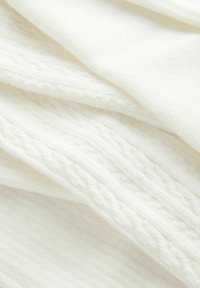 Weißer gestrickter Stoff mit einem strukturierten Muster, das erhöhte Kabeldetails und glatte Abschnitte aufweist, hervorgehoben durch weiche, leichte Fasern.