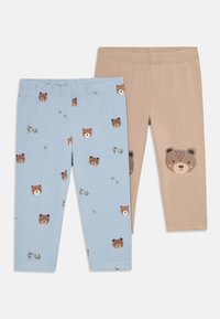 Twee paar peuterleggings, een beige met een groot berenhoofd op de knie, een lichtblauw met kleine berenhoofden en takjespatroon.