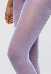 Διάφαντες, λαμπερές μοβ καλσόν με χαρακτηριστικό βαθμιαίας μετάβασης από αδιαφανές σε διάφανο. Ομαλή υφή με ελαφριά γυαλάδα.