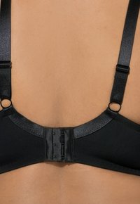 Sort bh-bag med justerbare stropper, en hægteen og glat stoftekstur mod en lys hudtone.