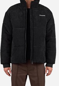 Giacca puffer in corduroy nera con collo alto, zipper anteriore e polsini a costine. Presenta un logo sul lato sinistro del petto e un design trapuntato.