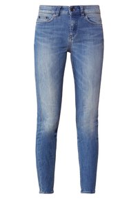 Jeans skinny de denim azul claro, que presentan una textura suave, diseño de cinco bolsillos, costuras cosidas y cierre de botón.