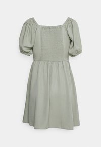 Vestido verde claro com mangas bufantes e decote quadrado. Apresenta um painel posterior franzido e uma saia fluida e pregueada. Textura de tecido suave.