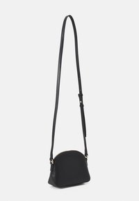 Schwarze Leder-Umhängetasche mit einer geschwungenen Form, goldfarbenem Reißverschluss und einem langen, verstellbaren Riemen. Glatte Textur und minimalistisches Design.