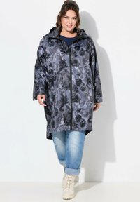 Voděodolný, oversized pláštěnka tmavě šedé barvy s jemným abstraktním vzorem, s kapucí a plným předním zipem.