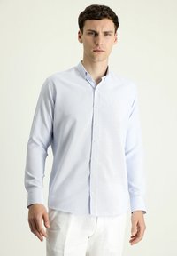 Camicia a bottoni azzurro chiaro con tessuto texturizzato, maniche lunghe e colletto classico; presenta bottoni bianchi lungo la parte anteriore.