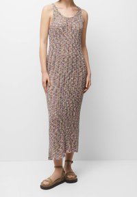 Vestido maxi de punto con un patrón texturizado en hilos multicolores. Presenta un escote amplio y tirantes, combinado con sandalias marrones.