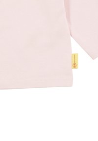 Light pink t-shirt with long sleeves, made from soft jersey fabric. Features a small yellow tag with red text at the hem.