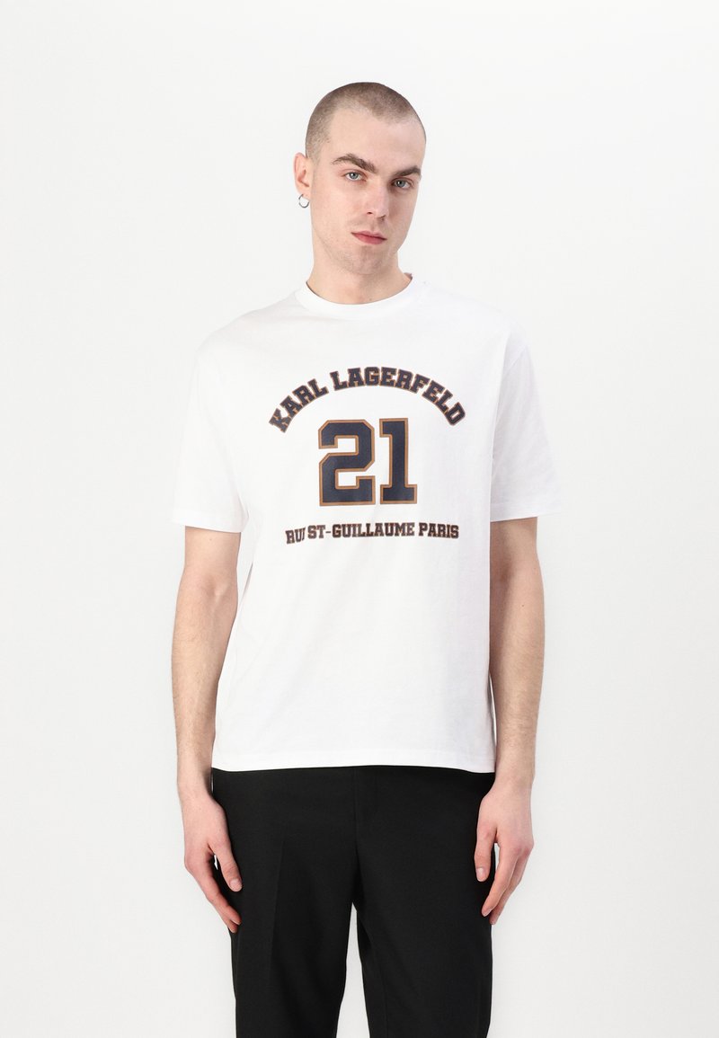 Hvit bomull T-skjorte med svart og gull trykt tekst. Har "KARL LAGERFELD," "21," og "RUE ST-GUILLAUME PARIS" i fet typografi.